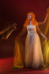 Old female actress with orange hair dancing in white dress with light show with yellow, orange and green lights around