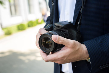 partial view of photojournalist in formal wear holding photo camera