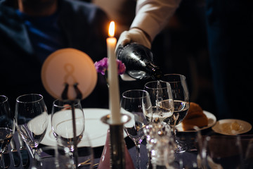 Pouring white wine from bottle into the wine glass.