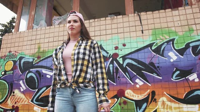 Portrait of young stylish woman graffiti artist on the graffiti wall background