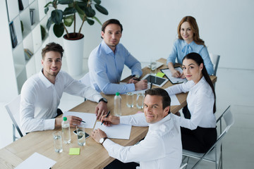 high angle view of smiling business colleagues at workplace with papers in office