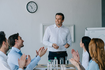business coworkers applauding to smiling mentor while having business training in office