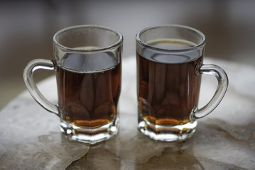 Two glass cups of Turkish black tea on granite table, blurred background.
