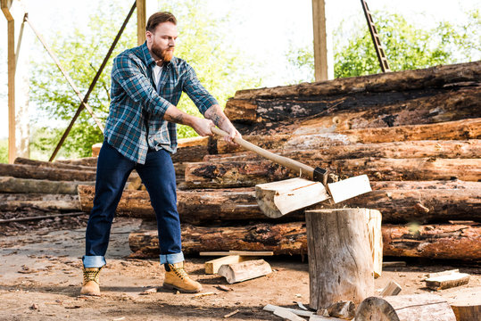 lumberjack in checkered shirt chopping log at sawmill