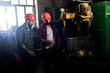 Fototapeta na wymiar carpenters in protective helmets using machine tool at sawmill