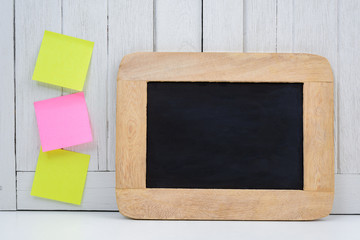 Chalkboard and blank sticky note, post note on Office desk white wooden vintage background