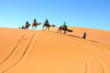 Fototapeta na wymiar サハラ砂漠でラクダに乗る観光客
