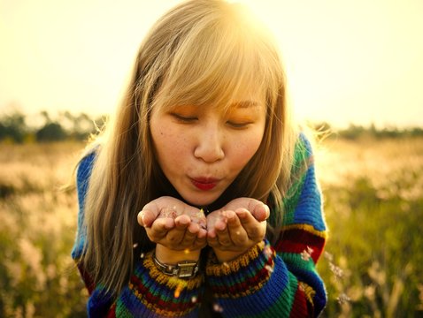 Woman Blowing Flower Petals Off Her Hands