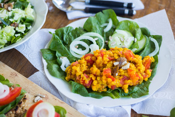 Red Indian cooked lentil beans with tomatoes, turmeric powder and spices. Served with fresh green vegetables: cucumbers, onion rings, spinach leaves Raw vegan vegetarian food. Healthy lunch, dinner