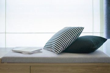 Comfortable seat next to window with pillows and books