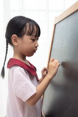 Asian Chinese little girl writing on blackboard