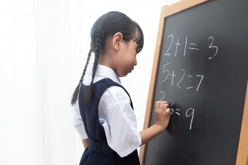Asian Chinese little girl writing on blackboard