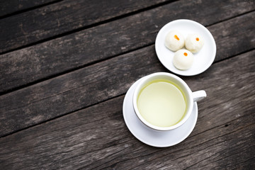 Herbal tea in white ceramic cup with chinese cake on vintage style old wooden table background, tea time break