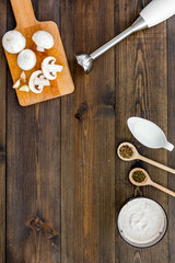 Cook cream soup with mushrooms. Champignon, cream, spices and blender on dark wooden background top view copy space
