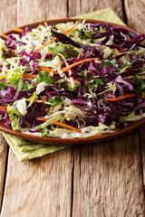 Delicious organic salad of white and red cabbage with carrots, herbs dressed with olive oil close-up. vertical