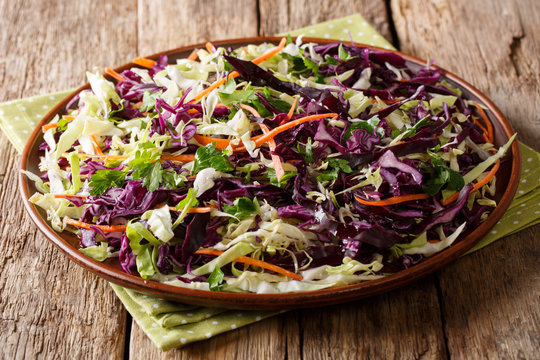 Mix salad of white and red cabbage with carrots, onions, herbs with olive oil close-up on a plate. horizonta