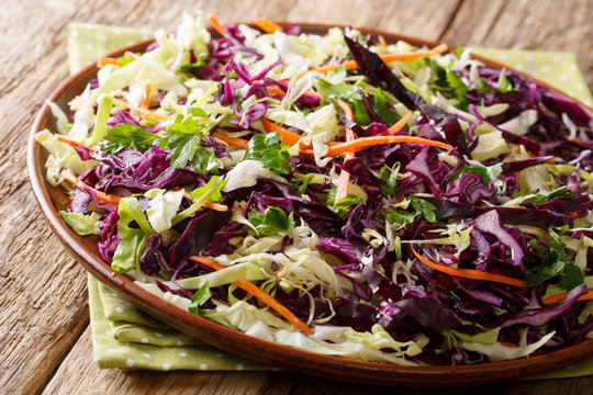 Healthy food: salad of white and red cabbage with carrots, herbs with olive oil close-up. horizontal