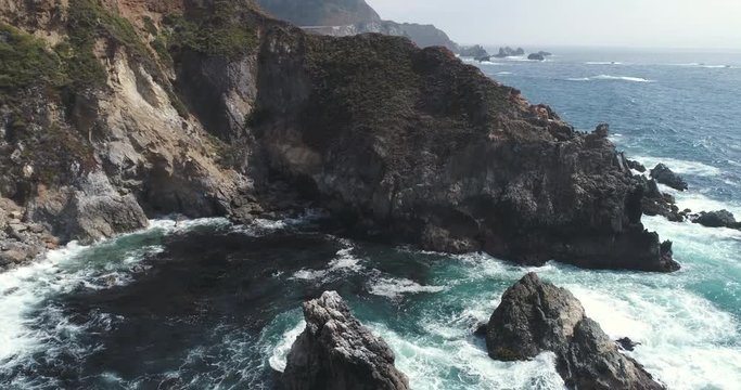Flight over of rocky coastline. Aerial of Ocean shore, waves crashing cliffs