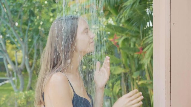 Yong pretty woman taking shower outdoor at swimming pool area in slow motion