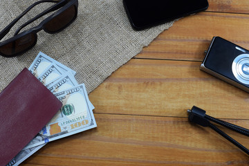 passport with money (dollars) for vacation, camera, glasses and different things on the table