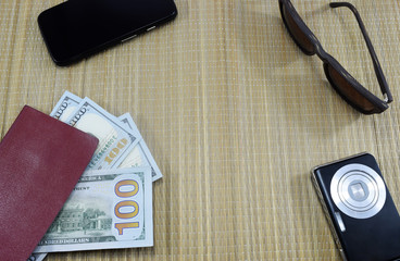passport with money (dollars) for vacation, camera, glasses and different things on the table