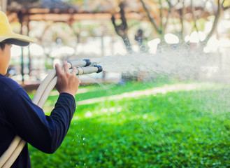 man pouring water on the grass in the garden