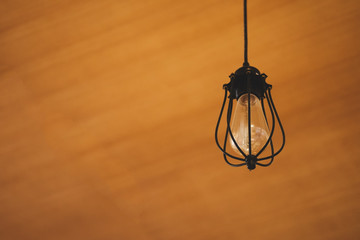 Vintage Edison light bulb hanging over against wooden background in cafe.