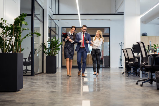 Business partners walking down in office building and discussing work
