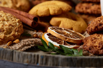 Conceptual composition with assortment of cookies and cinnamon on a wooden barrel, selective focus, close-up