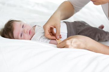 mother or doctor or nurse is putting a plaster on the baby hand