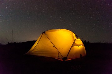 Yellow illuminated tent under night sky. Camping at night. Version 2.