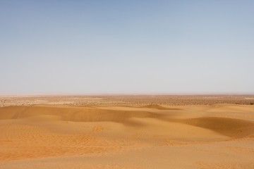 Dasht-e Kavir desert in Iran, featuring endless sand dunes under a clear blue sky.