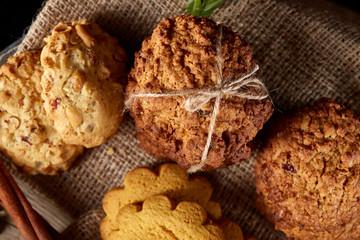 Conceptual composition with assortment of cookies on burlap napkin on a wooden barrel, selective focus, close-up