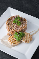 Buckwheat porridge with dietary meat on a white plate is tenderly served