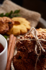 Conceptual composition with assortment of cookies and cinnamon on napkin on a wooden barrel, shallow depth of field
