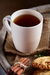Fotobehang White porcelain cup of hot tea, cookies and spicies on a wooden barrel, selective focus, close-up, vertical. © Aleksey