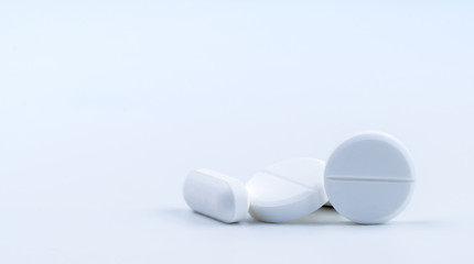 Pile of white round and oblong shape tablet pills isolated on white background. Pharmaceutical...