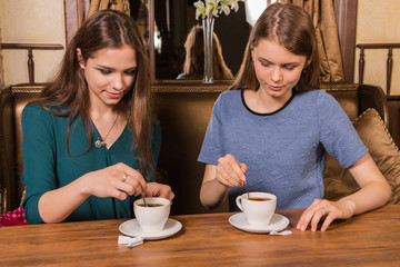 Two happy women drinking coffee in cafe