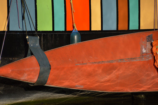 sidekick: orange colored canoo hanging near a striped houseboat