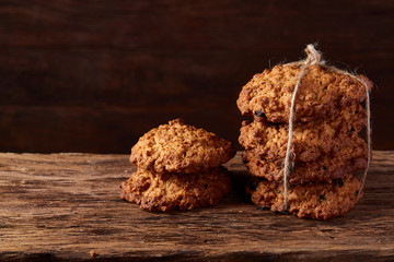Bunch of chocolate biscuits on a flat piece of wood over rustic wooden background, close-up, selective focus.