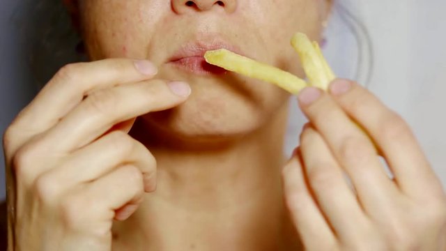 close up shot of a woman's mouth, a lady looks hungry and puts her fries in her mouth