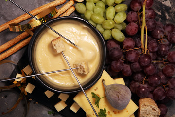 Gourmet Swiss fondue dinner on a winter evening with assorted cheeses on a board alongside a heated pot of cheese fondue