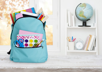 School backpack on wooden table over children room interior background