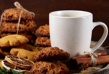 Conceptual festive composition with a cup of hot tea, cookies and spicies on a wooden barrel, selective focus, close-up