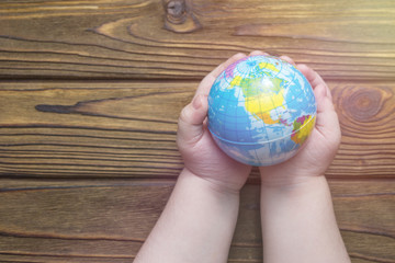 globe in hands on a wooden background.