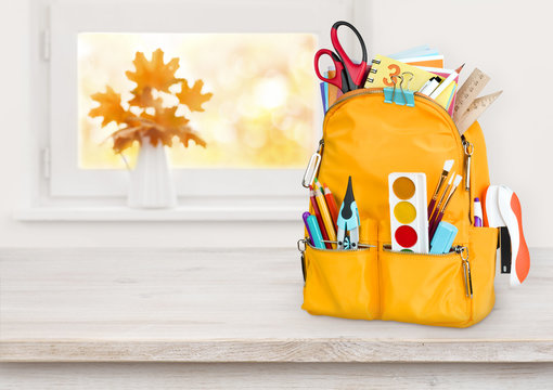 Yellow school bag on wooden table over autumn windowsill background