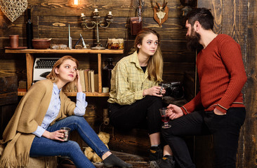 Fototapeta na wymiar Friends, family spend pleasant evening, interior background. Sincere conversation concept. Girls and man on happy faces hold metallic mugs, talking. Family enjoy conversation in gamekeepers house