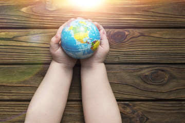 globe in hands in the sun on a wooden background