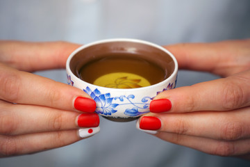 Fototapeta na wymiar Cropped shot of woman holding traditional chinense teacup with oolong green tea.
