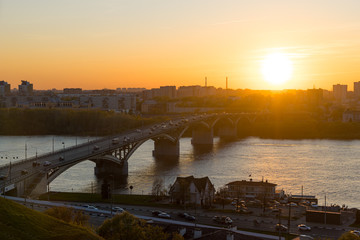 View from the high on Nizhny Novgorod city in Russia, Kanavinsky Bridge over the Oka River at sunset, moving cars on the bridge and on the road